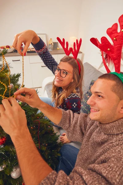 Happy couple decorating tree for New Year\'s / Christmas eve.