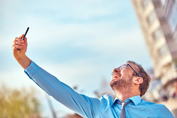 Divertido hombre de negocios con pulgares hacia arriba mientras usa el teléfono inteligente al aire libre —  Fotos de Stock