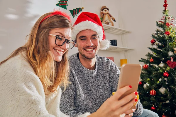 Pareja feliz disfrutando de Año Nuevo / Nochebuena con teléfono celular —  Fotos de Stock