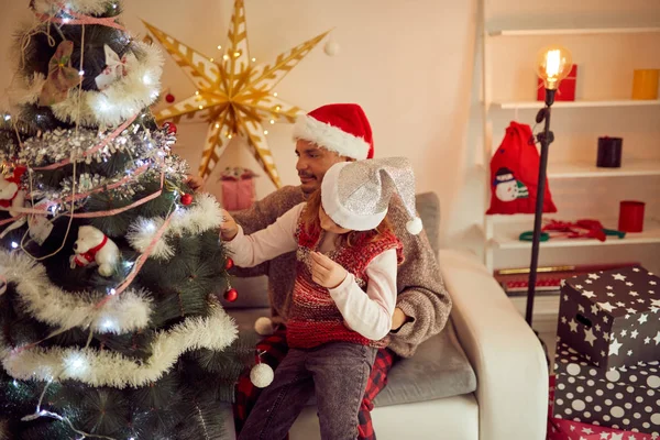 Vater und Tochter schmücken gemeinsam Weihnachtsbaum zu Hause. — Stockfoto