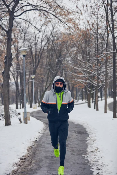 Człowiek jogging w zimnej zimie śnieżny dzień na zewnątrz. — Zdjęcie stockowe