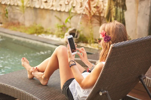 Ragazza che utilizza il cellulare mentre si trova su una sala coperta della piscina — Foto Stock