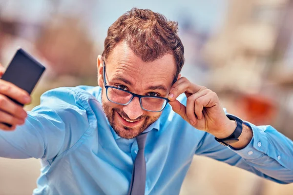 Divertido hombre de negocios con pulgares hacia arriba mientras usa el teléfono inteligente al aire libre —  Fotos de Stock