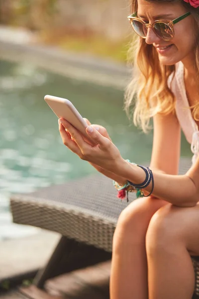 Meisje met behulp van mobiele telefoon liggend op een zwembad dek Lounge — Stockfoto