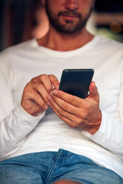 Muž sedí na pohovce terasu a používat mobilní telefon. — Stock fotografie