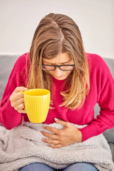 Ziek meisje Holding Cup en het drinken van koffie/thee op een bank. — Stockfoto