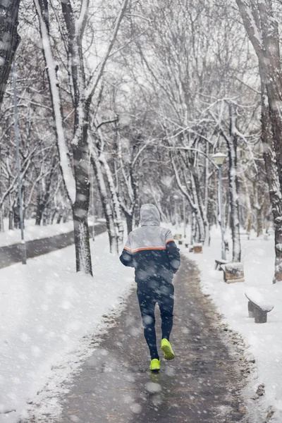 Homem correndo em um inverno frio dia nevado ao ar livre . — Fotografia de Stock
