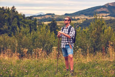 Çayırda kemerinde bıçakla poz veren yürüyüşçü.