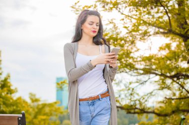 Kentsel ortamda cep telefonu kullanarak sevimli genç kadın.