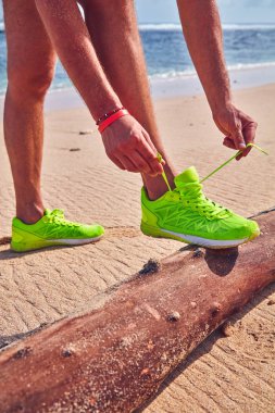 Bir tropikal egzotik plajda çalışan Sneakers bağlama adam.
