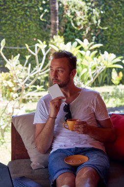 Adam cep telefonu ve laptop kullanarak TH kahve/çay içme