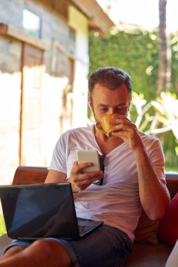 Adam cep telefonu ve laptop kullanarak TH kahve/çay içme