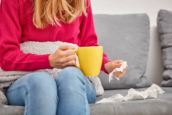 Niña enferma sosteniendo la taza y bebiendo café / té en un sofá . — Foto de Stock