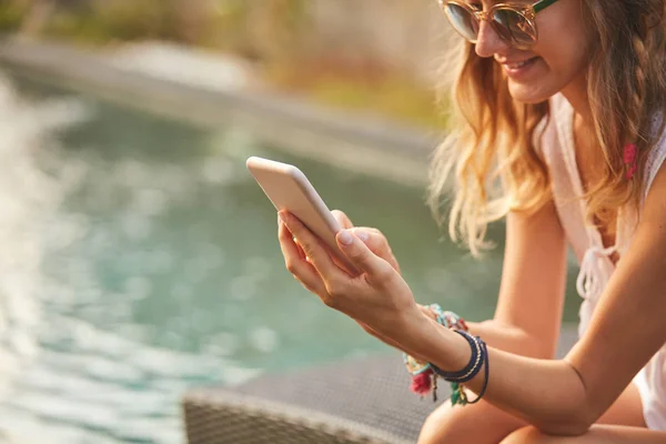 Meisje met behulp van mobiele telefoon liggend op een zwembad dek Lounge — Stockfoto