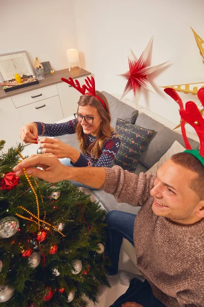 Glückliches Paar schmückt Baum für Neujahr / Heiligabend. — Stockfoto