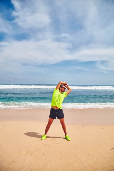 Deportista estirándose en una exótica playa tropical después de correr / —  Fotos de Stock