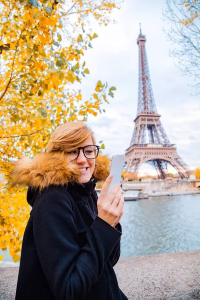 Chica usando el teléfono celular con el fondo de la ciudad de París y la torre Eiffel — Foto de Stock