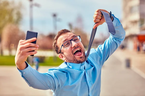 Divertido hombre de negocios enojarse mientras usa el teléfono inteligente al aire libre . —  Fotos de Stock