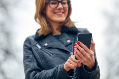 Sevimli genç kadın kullanarak Cellphone açık havada.