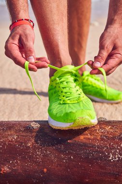 Bir tropikal egzotik plajda çalışan Sneakers bağlama adam.