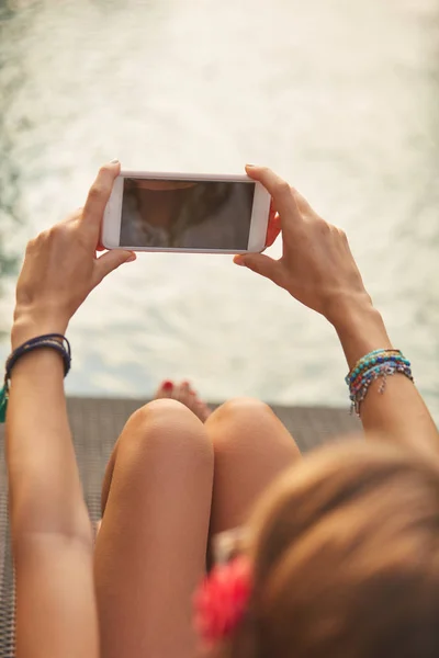 Chica usando el teléfono celular mientras está acostado en un salón de cubierta de piscina — Foto de Stock