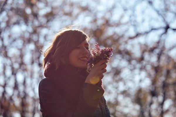Csinos fiatal lány illatú szép csokor virágot a természetben. — Stock Fotó