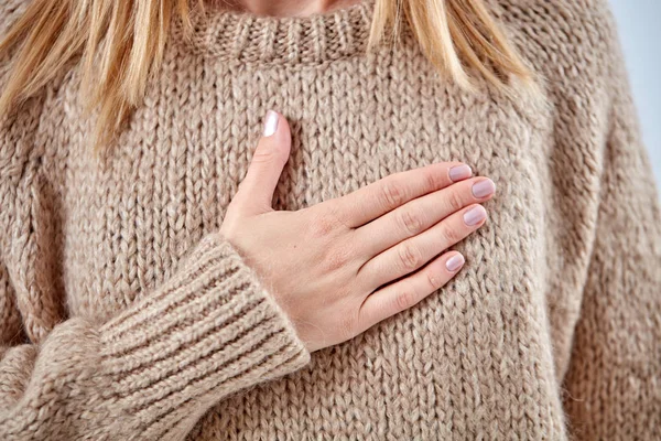 Young woman with heart problem holding chest.