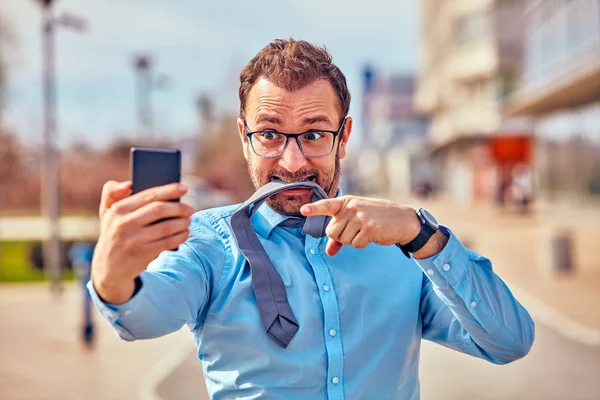 Divertido hombre de negocios enojarse mientras usa el teléfono inteligente al aire libre . —  Fotos de Stock