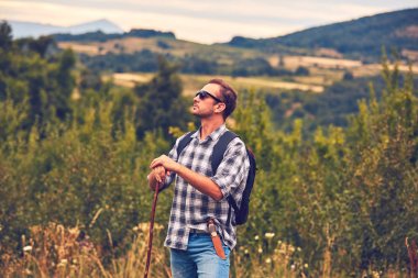 Çayırda kemerinde bıçakla poz veren yürüyüşçü.