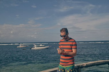 Okyanus plajında cep telefonu kullanan adam.