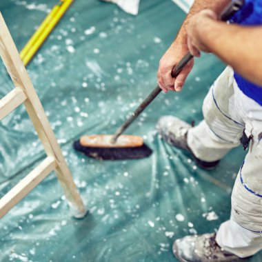 İşçi bir yenileme sırasında kir Temizleme için süpürge kullanarak Hou