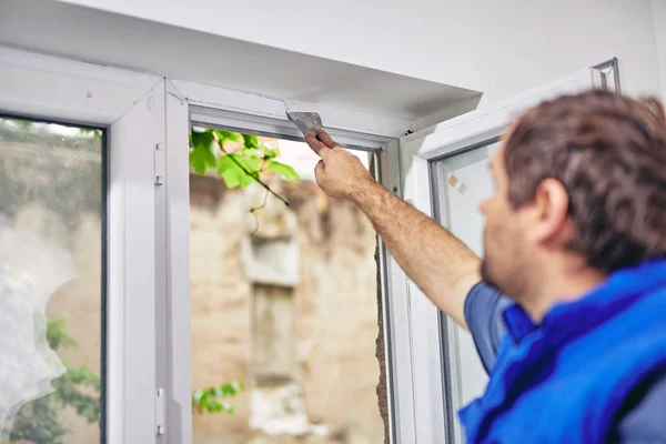 Worker using silicone for walls and widnows inside the house - r