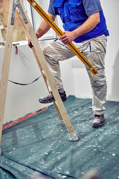 Εργαζόμενος στέκεται στην σκάλα και ανακαινίζοντας το σπίτι. — Φωτογραφία Αρχείου