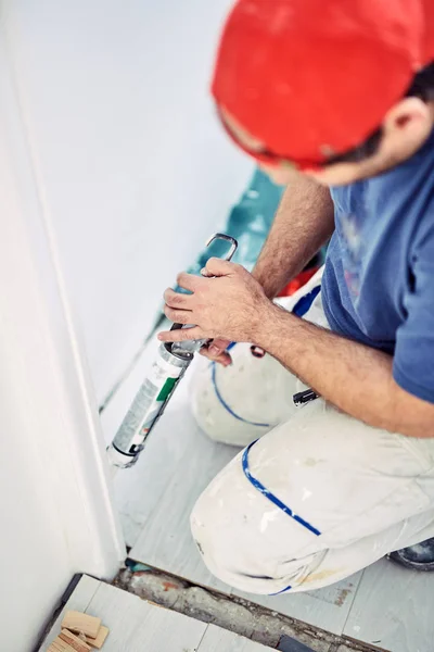 Trabajador que usa silicona para paredes y marco de puerta dentro de la casa — Foto de Stock