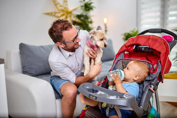 Single dad playing at home with a baby and dog.