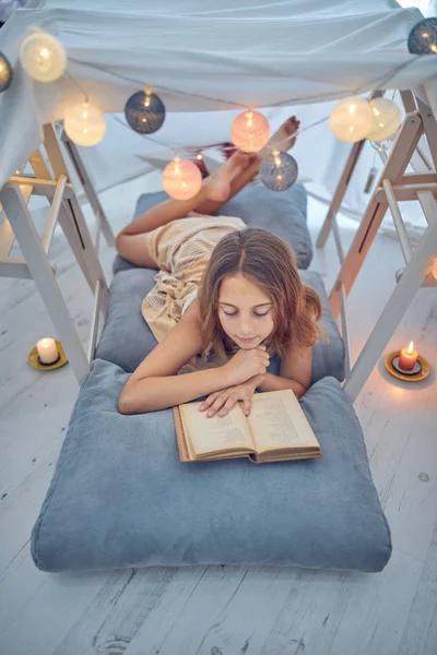 Маленькая 10-летняя девочка читает классическую книгу под домашней работой — стоковое фото
