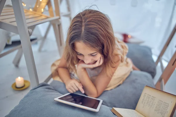 Piccola bambina di 10 anni utilizzando tablet sotto la sua tenda fatta in casa in — Foto Stock