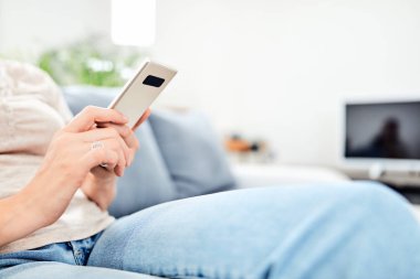 Evin içinde akıllı telefon kullanan bir kadın..