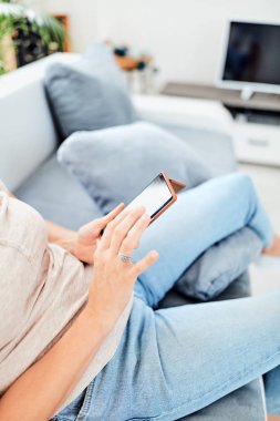 Evin içinde akıllı telefon kullanan bir kadın..