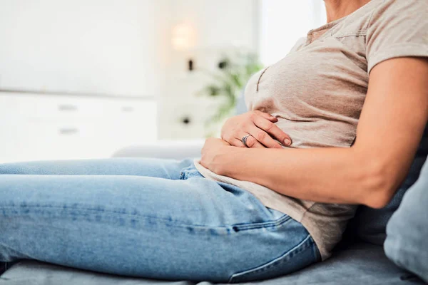Mujer con problemas de estómago / problemas mientras está sentada en el sofá — Foto de Stock