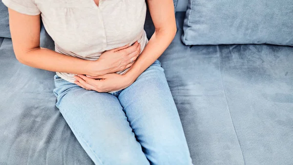 Wanita dengan masalah perut saat duduk di sofa — Stok Foto