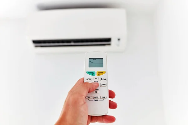 Moderno climatizzatore con una mano che tiene un telecomando . — Foto Stock