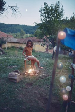 Küçük kız bahçede kamp ateşi yakıyor..