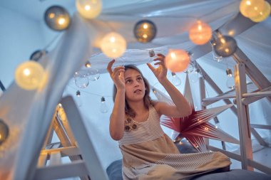 Küçük kız oynuyor ve odada çadır kuruyor..