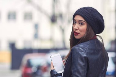 Şapkalı ve cep telefonlu genç bir kadın..