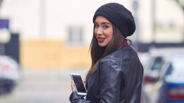 Şapkalı ve cep telefonlu genç bir kadın..