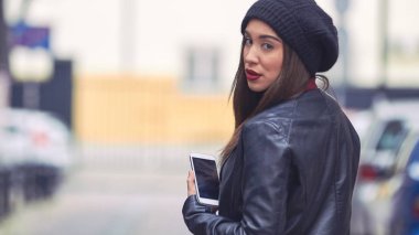 Şapkalı ve cep telefonlu genç bir kadın..