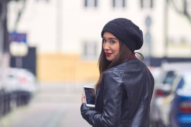 Şapkalı ve cep telefonlu genç bir kadın..