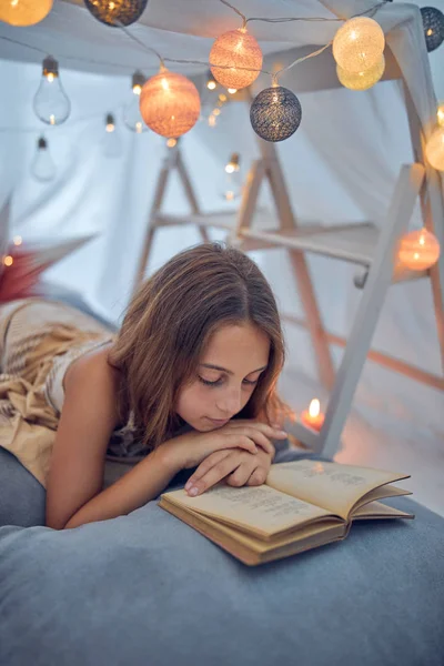 Piccola bambina di 10 anni che legge il libro classico sotto il suo fatto in casa — Foto Stock