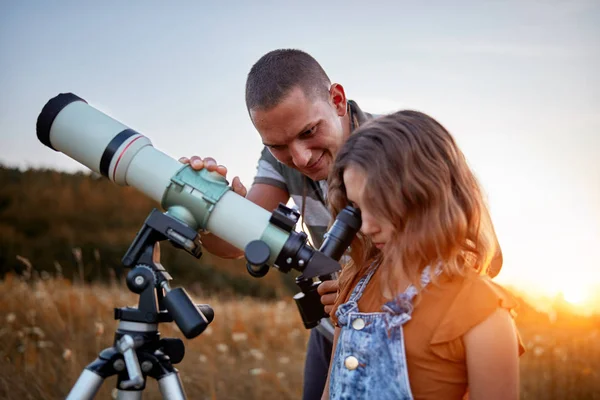 Far och dotter observerar himlen med ett teleskop. — Stockfoto